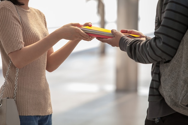 The girl is giving a book to a guy. He is looking at her happily