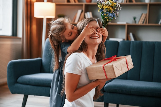 Foto la ragazza sta dando la scatola con un regalo la giovane madre con sua figlia è insieme all'appartamento