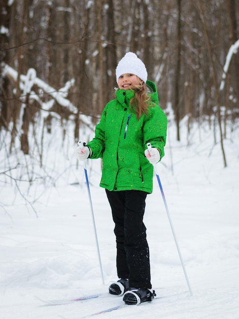 Girl is in a good mood on the slopes in the winter forest.