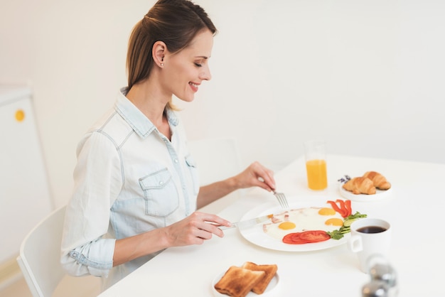 The girl is having breakfast in the kitchen 