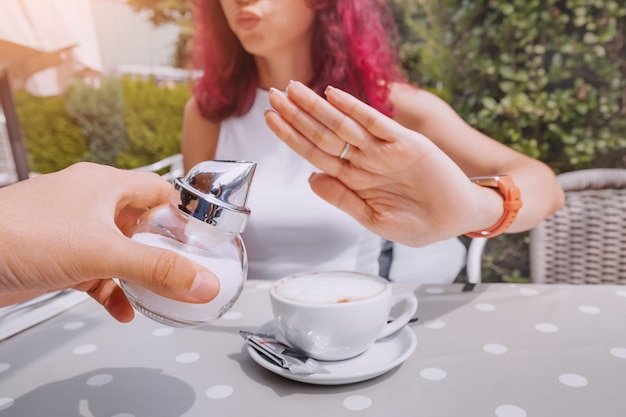 少女は健康的な食生活をしており、コーヒーに砂糖を加えることを拒否しています 過剰な炭水化物と糖尿病による病気の概念