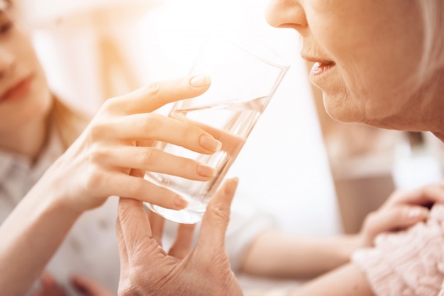 写真 女の子は水のガラスを持つ女性を助けています。