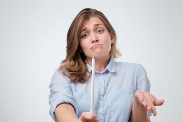 The girl is holding a blunt white pencil in her hand and shrugging her shoulders helplessly