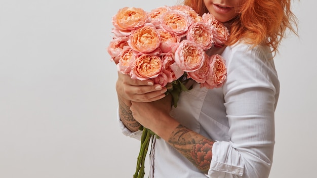 The girl is holding a bouquet of pink roses