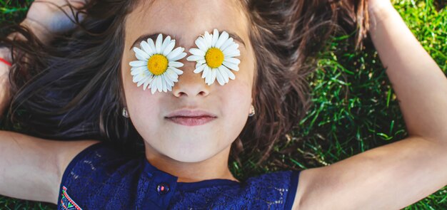 사진 소녀는 그녀의 손에 카모마일 꽃을 들고 있다. 선택적 초점입니다. 자연.