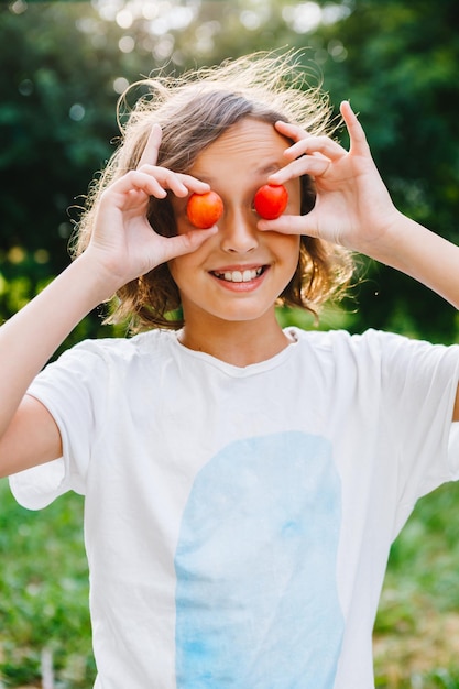 Девушка держит помидоры черри, закрывает глаза и улыбается