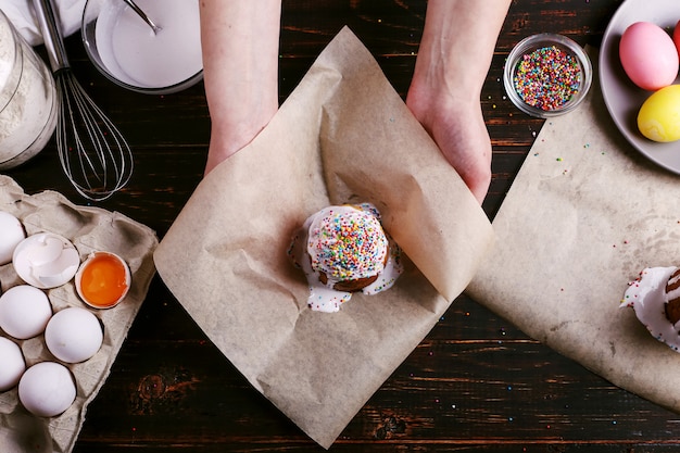 The girl is holding Easter baked goods with icing and colored powder