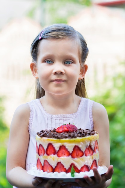 女の子はフレンチケーキを保持しています。