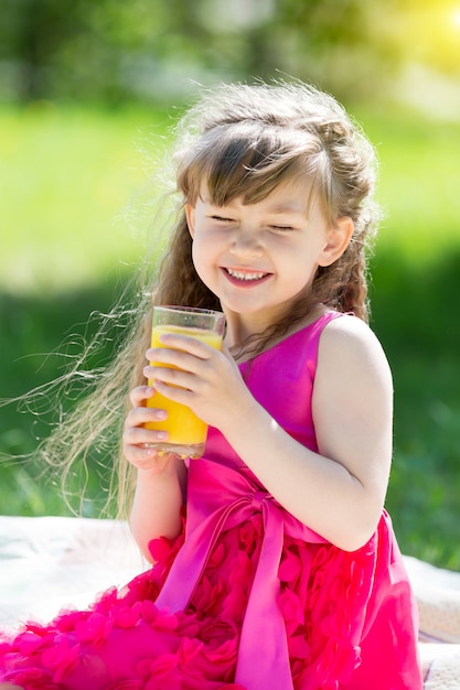 The girl is holding a glass with juice in her hands.