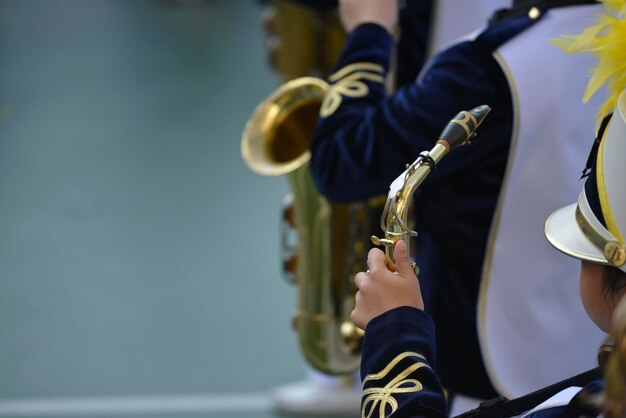 A girl is holding a gold saxophone in a marching bad