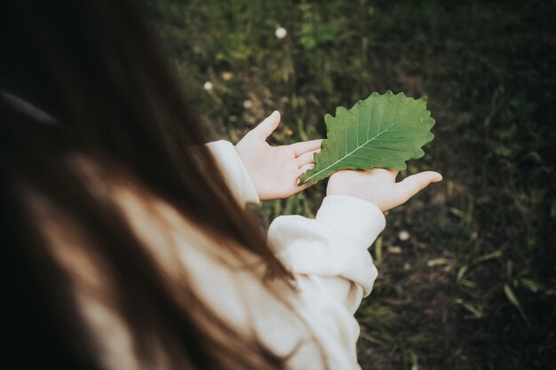 Foto la ragazza tiene tra le mani una foglia verde