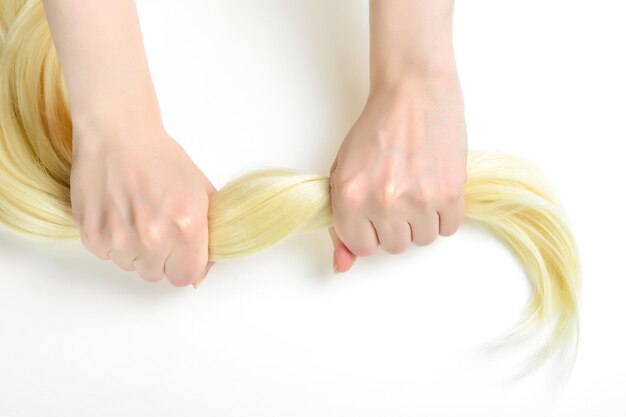 Girl is holding her healthy strong blond hair on white background