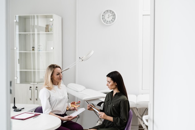 Photo girl is holding iud intrauterine device and listen gynecologist about process installing in uterus gynecology consultation