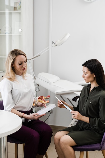 Photo girl is holding iud intrauterine device and listen gynecologist about process installing in uterus gynecology consultation