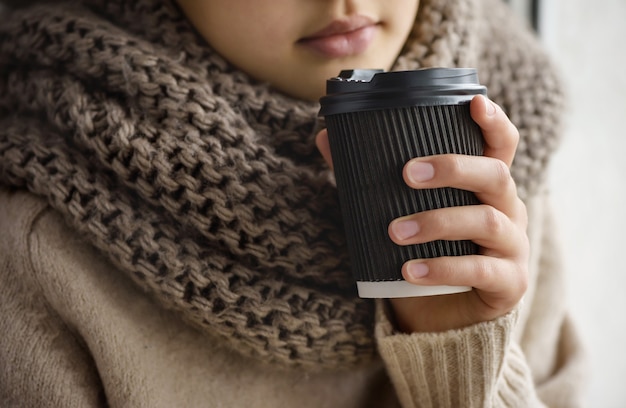 Photo girl is holding a paper cup with coffee