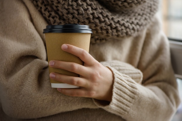 Girl is holding a paper cup with coffee