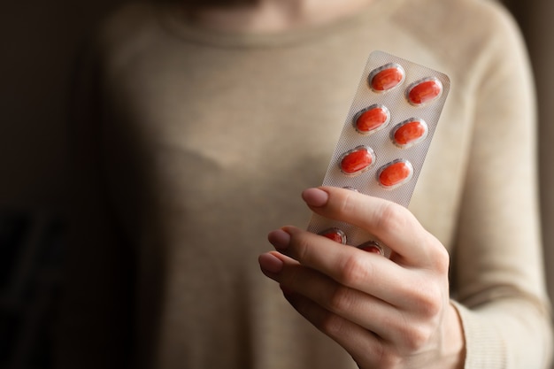 The girl is holding plates with pills on a dark background