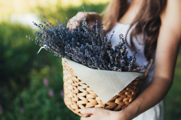 女の子は木箱に紫色のラベンダーの花を持っています。高品質の写真