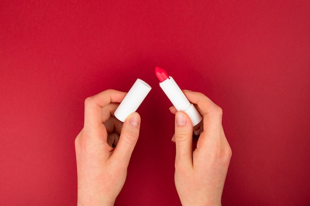여자는 빨간 립스틱을 들고있다. 제품을 평가하고 평가합니다.
