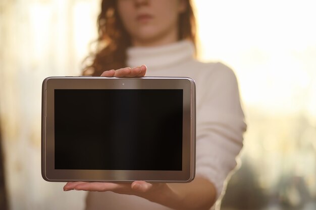 Foto la ragazza tiene in mano un tablet. la ragazza ha un computer con uno schermo in mano. le mani tengono il display con uno spazio vuoto.