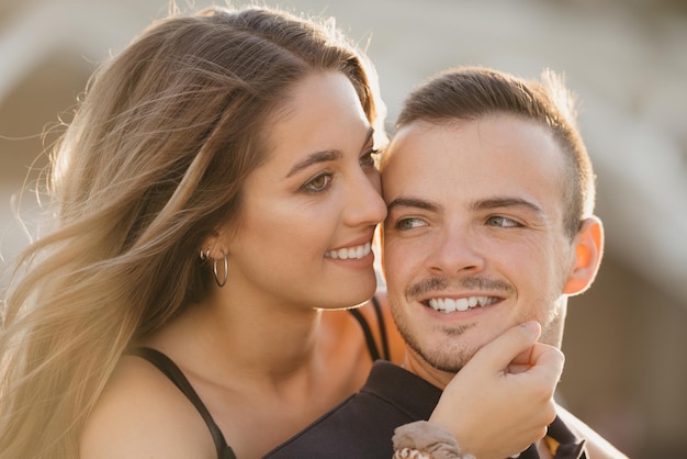 A girl is hugging her boyfriend from the back in the modern urban space in Spain