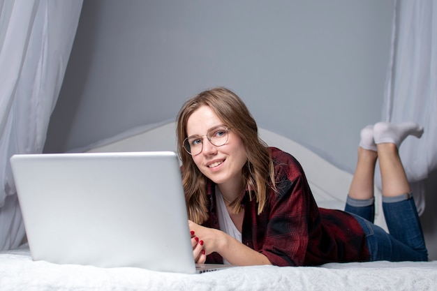 Girl is lying in bed with a laptop