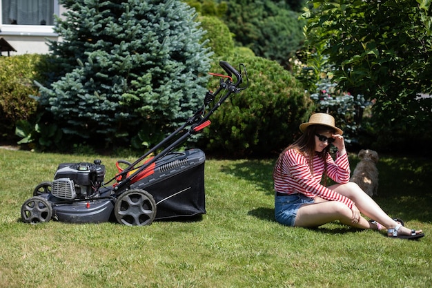 A girl is lying on the lawn resting after mowing the grass