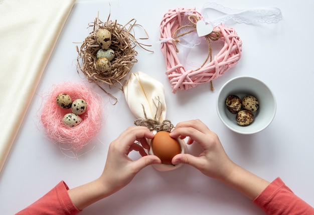 Girl is make wickerwork of beads and eggs for easter