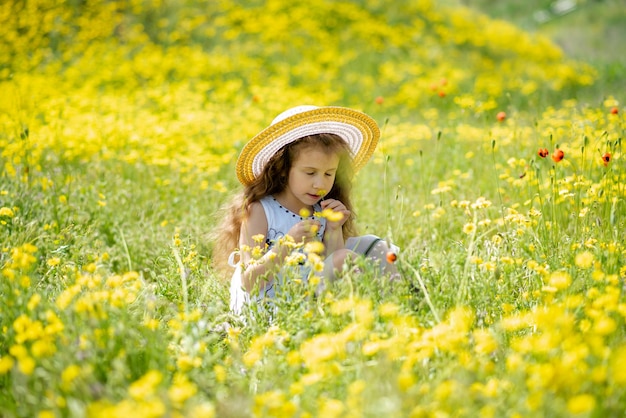 女の子は黄色い花とポピーのある牧草地にいますペイント自然