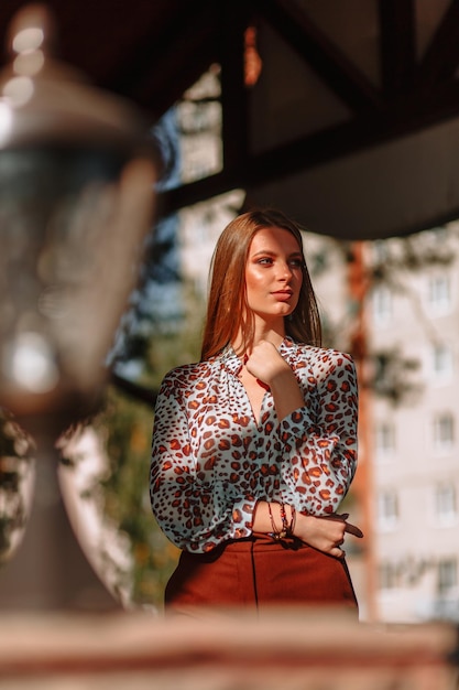 The girl is a model showing fashionable outerwear on the street on the veranda of a summer cafe Clothes for the showroom