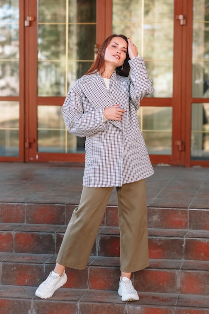 The girl is a model showing fashionable outerwear on the street on the veranda of a summer cafe Clothes for the showroom