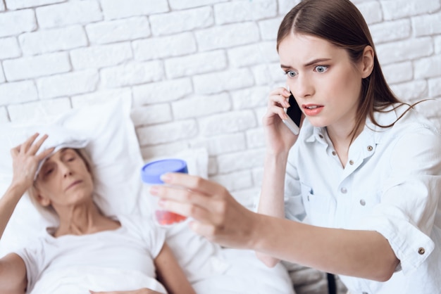 Girl is nursing elderly woman in bed at home