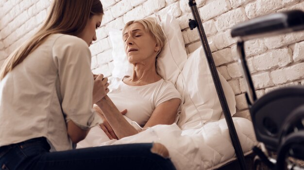 Girl is nursing elderly woman in bed at home