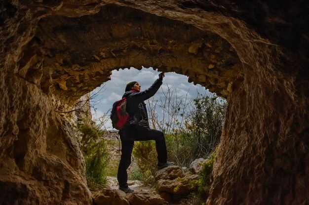 A girl is observing the rocks on the entrance of a cave