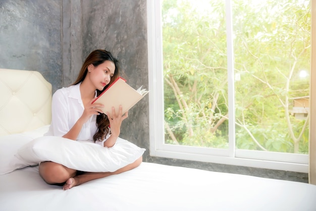 The girl is reading the book in bed after waking