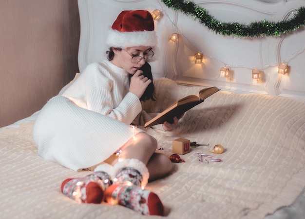 The girl is reading a book lying on the bed