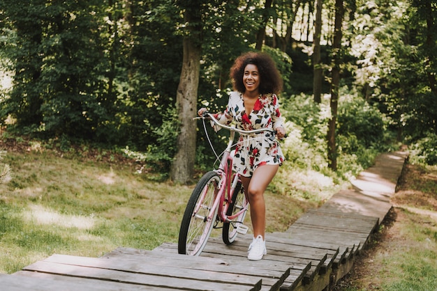 La ragazza sta rotolando la bici sul passerella in legno.