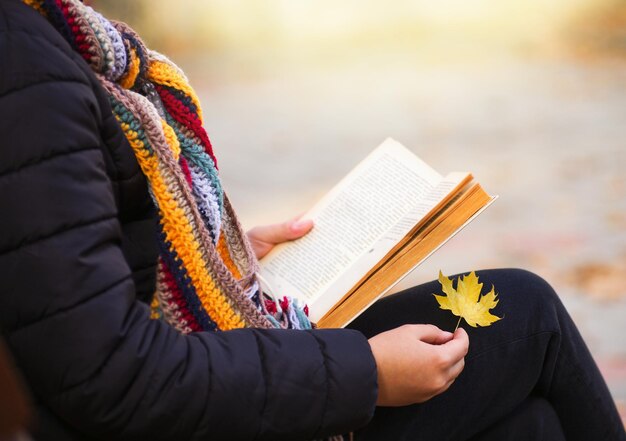 La ragazza è seduta su una panchina e sta leggendo un libro