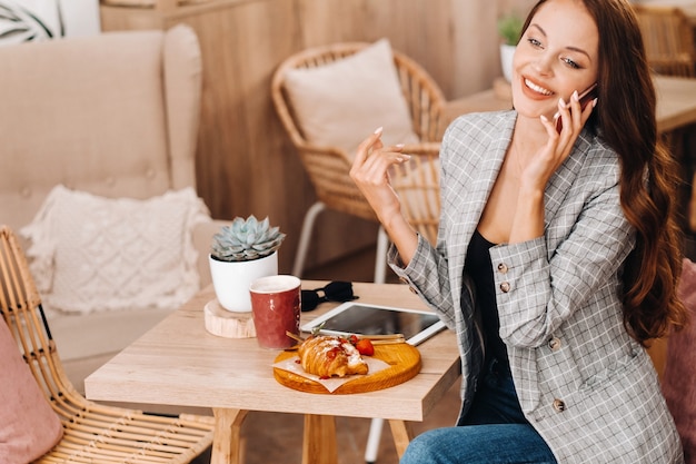 A girl is sitting in a cafe and talking on the phone