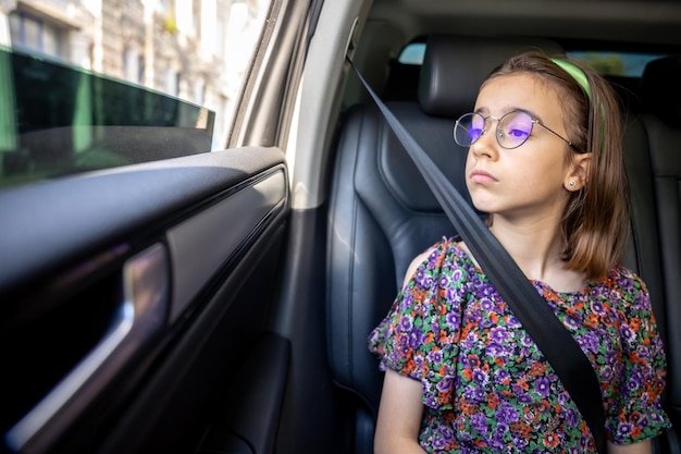 The girl is sitting in the car on the way to school