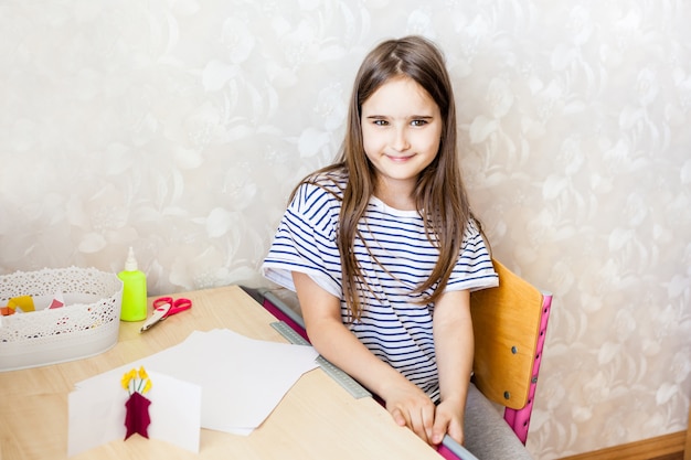 Девушка сидит за письменным столом, рисует, делает домашнее задание, прибирает, пишет, бумага, маркеры
