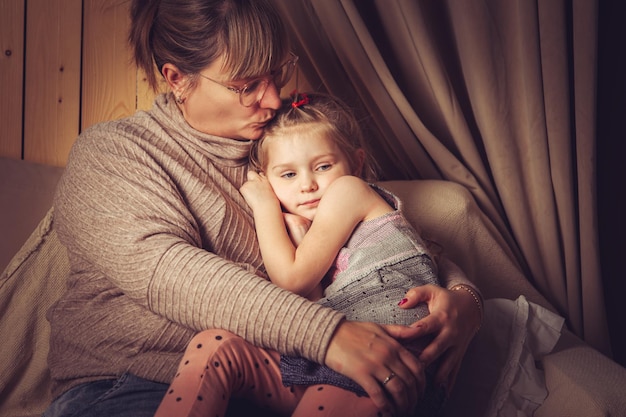 The girl is sitting in her mother's arms. Family idyll.