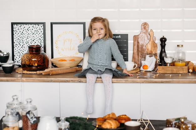 Girl is sitting on kitchen table.