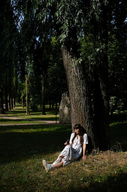 The girl is sitting near the tree