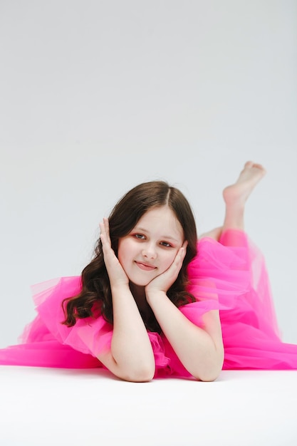 The girl is smiling in a pink dress on a white background