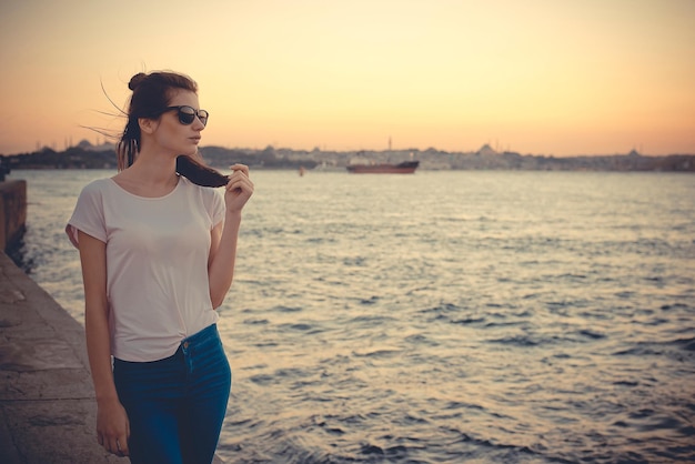 The girl is standing on the waterfront near the seaport