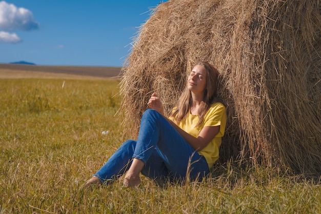 A girl is sunbathing in the hay. village life: harvesting hay for the winter. animal feed.
