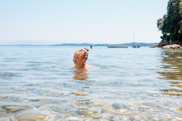 Girl is swimming, has fun. Family summer vacation. Kids swim in ocean water. Water fun