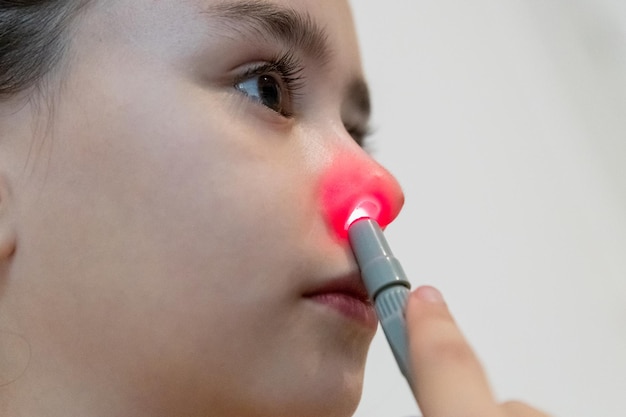 A girl is treating her nasal passage with an infrared light device