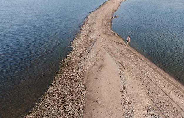 The girl is walking along the spit in the sea Air view